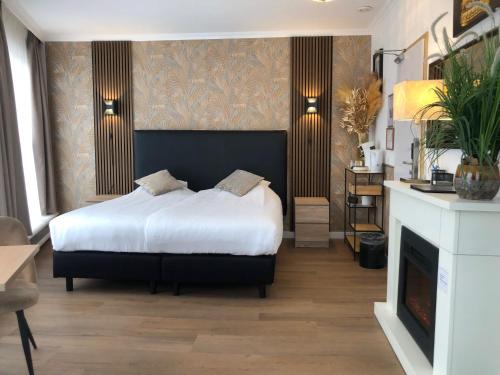 a bedroom with a large bed and a fireplace at Hotel de Keizerskroon Hoorn in Hoorn