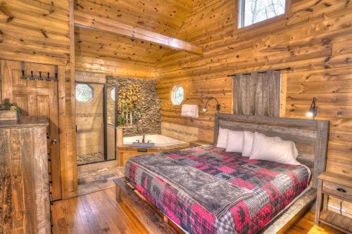 een slaapkamer met een bed en een bad in een hut bij Luxury Cabin Sleeps 8 with creekside fire pit near Helen GA in Cleveland