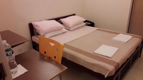 a small room with a bed with pink pillows and a table at Binara House - Nugegoda, Colombo in Nugegoda