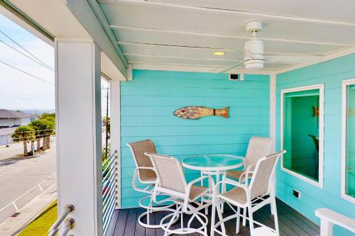 ein blaues Haus mit einem Tisch und Stühlen auf einer Veranda in der Unterkunft Pirates Pier in Kure Beach