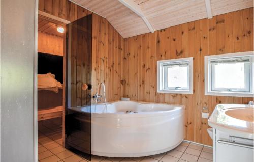 Binderup StrandにあるBeautiful Home In Bjert With 3 Bedrooms, Sauna And Wifiの木製の壁のバスルーム(白い大型バスタブ付)