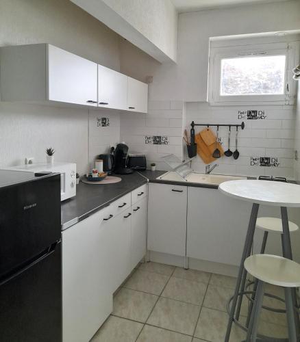 une petite cuisine avec des armoires blanches et une table dans l'établissement Studio centre ville - La plage à 1 minute, à Royan