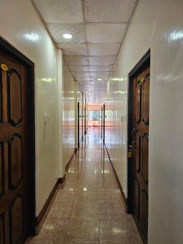 an empty hallway with two doors and a tile floor at Hotel SELLA & Rest in Kilinochchi