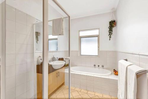 a white bathroom with a tub and a sink at Bayside Bungalow in Glenelg