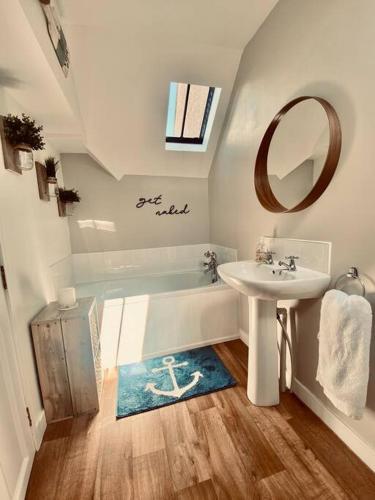 a bathroom with a sink and a bath tub at Cullen Seaside Cottage in Cullen