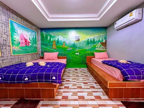 two beds in a room with a painting on the wall at สิชล บ้านอุ๊ รีสอร์ท in Sichon