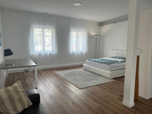 a white bedroom with a bed and a desk at Grosse Einzimmerwohnung/Büro/Showroom in Seengen