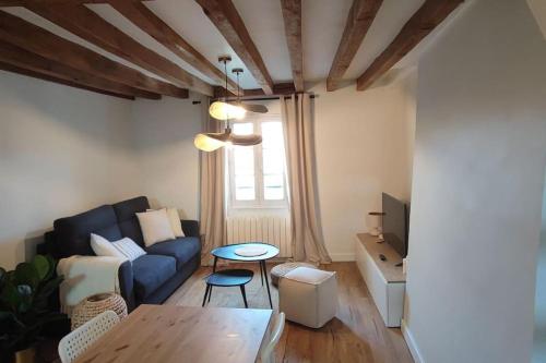 un salon avec un canapé bleu et une table dans l'établissement Appartement de charme au cœur de ville, à Magny-en-Vexin