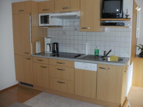 eine Küche mit Holzschränken, einer Spüle und einer Mikrowelle in der Unterkunft Haus Panorama in Sankt Leonhard im Pitztal