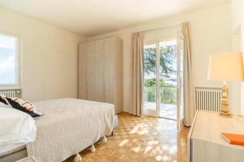 a bedroom with a bed and a sliding glass door at Villa dei Lauri - villa vista lago con piscina in Salò
