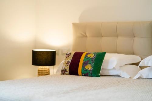 a white bed with a green pillow and a lamp at Villa dei Lauri - villa vista lago con piscina in Salò