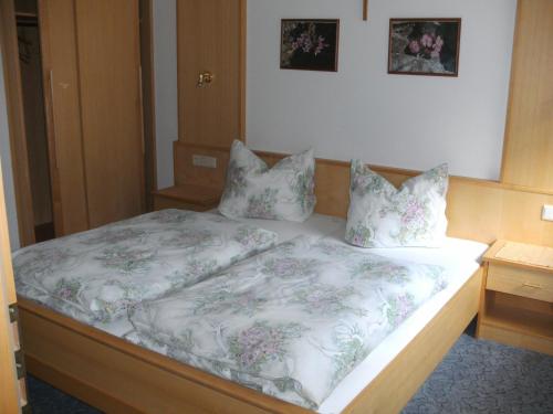 1 Schlafzimmer mit einem Bett mit geblümter Bettwäsche und Kissen in der Unterkunft Haus Panorama in Sankt Leonhard im Pitztal