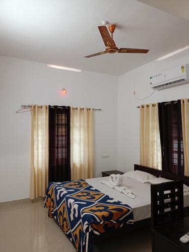 a bedroom with a bed and a ceiling fan at Enna homestay in Varkala