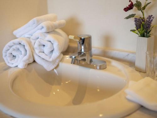 Hotel New Gaea Ube في يوبي: مغسلة الحمام فوقها مناشف