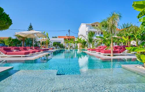 una piscina en un complejo con sillas y sombrillas rojas en Èmar Corfu, en Arillas