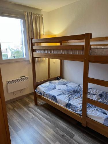 une chambre avec deux lits superposés et une fenêtre dans l'établissement Maison le long du canal du Midi, à Béziers