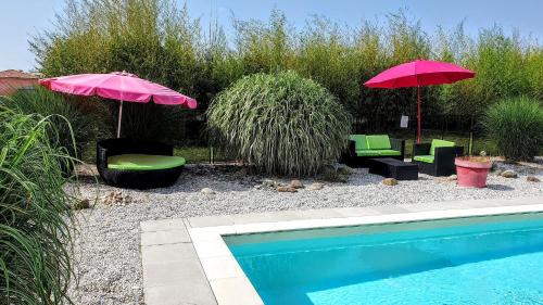 two umbrellas and chairs next to a swimming pool at Gîte Mara des Bois - Domaine du Pi geonnier de Saint-Vincent in Bourran