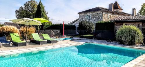 a swimming pool with green chairs and an umbrella at Gîte Mara des Bois - Domaine du Pi geonnier de Saint-Vincent in Bourran