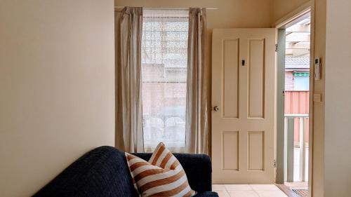 a living room with a couch and a large window at Learmonth Guesthouse - Queenscliff in Queenscliff
