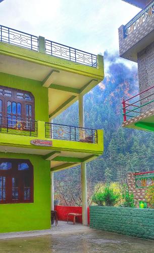 a building with two balconies and a view of a mountain at Little Hamlet Choj in Kasol