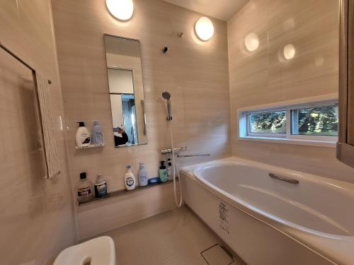 a bathroom with a tub and a toilet and a sink at guesthouse ONAKA in Mimase