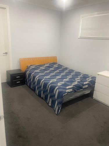 een slaapkamer met een bed met een blauw en wit dekbed bij Private room in shared house in Wollert