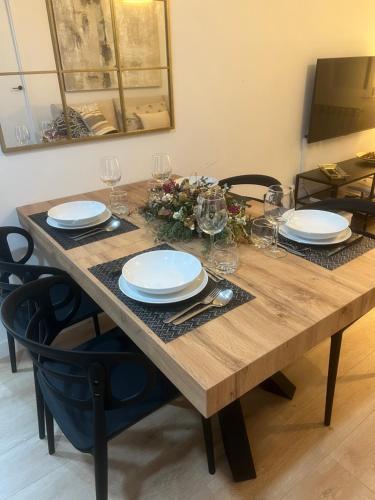 una mesa de madera con platos y copas de vino. en Capricho Lostal en Zaragoza