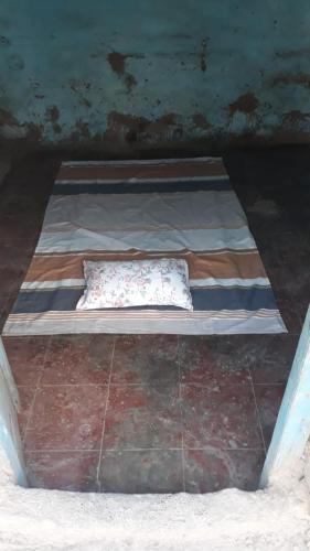 a small bed with a pillow on top of it at Mud House in Miraj