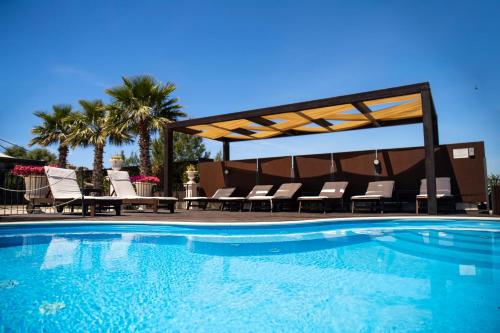 a swimming pool with chairs and a gazebo at Relais Villa Giuliana in Licata
