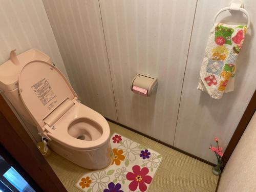 a bathroom with a toilet and a door with flowers on the floor at Shinshulanson in Nagano