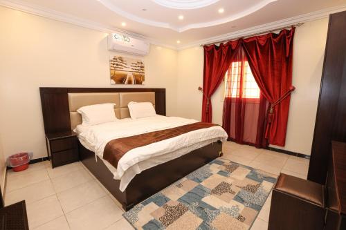 a bedroom with a bed and a red curtain at Taraf Al Asalah Villas in An Nimāş