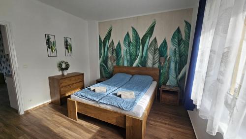 een slaapkamer met een bed en een muurschildering van bladeren bij Menta Holiday Home in Badacsonytomaj
