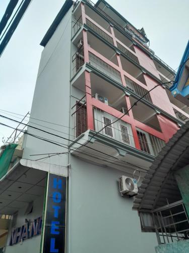 - un bâtiment rose et blanc avec un balcon dans l'établissement NHÀ NGHỈ TRÀ MY, à Vu Bản