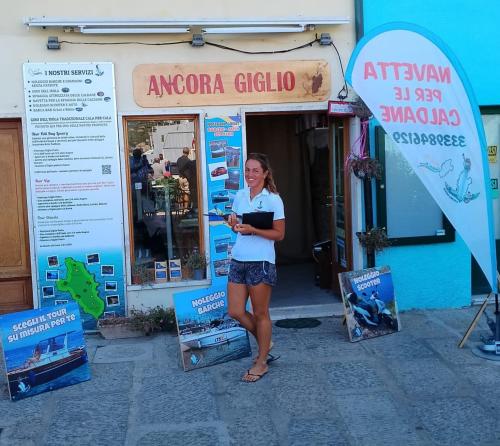 a woman is standing in front of a store at ANCORA GIGLIO home in Giglio Porto