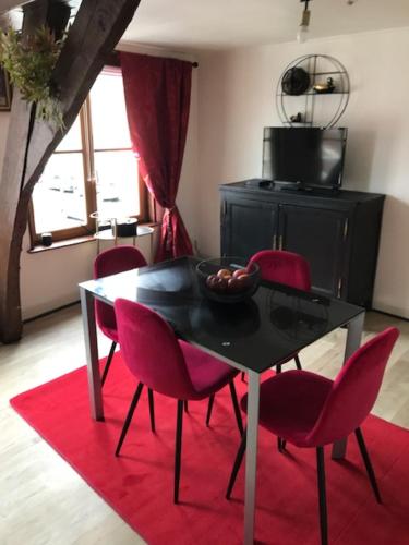 une salle à manger avec une table noire et des chaises rouges dans l'établissement Les Dames au chapeau vert, à Saint-Omer