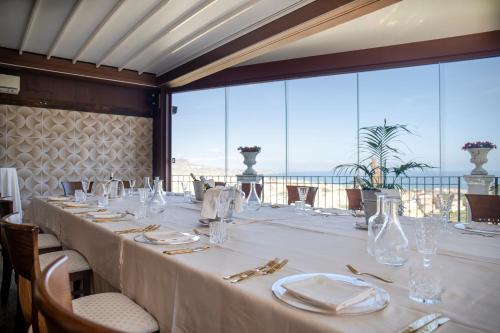 a long table in a restaurant with a view of the ocean at Relais Villa Giuliana in Licata