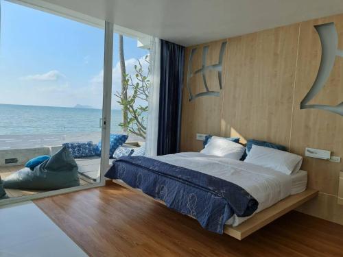 Luxtalay beachhouse villa في Ban Thung Makham: غرفة نوم مع سرير وإطلالة على المحيط