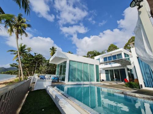 Luxtalay beachhouse villa في Ban Thung Makham: منزل به مسبح بجوار المحيط