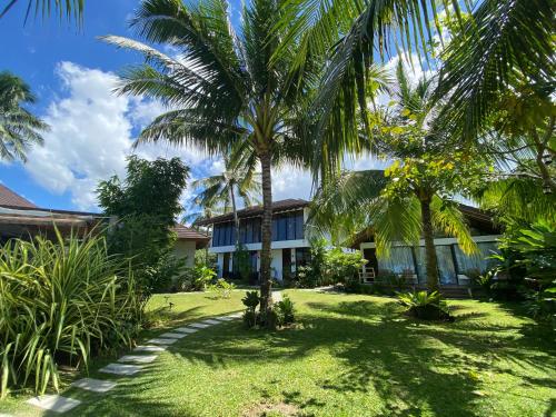 a house with palm trees in front of a yard at Amila Dive Beach Resort in Sipalay