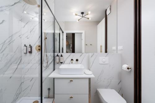La salle de bains blanche est pourvue d'un lavabo et d'une douche. dans l'établissement Apartments Wroc'LOVE by me & Mosiężna & Free Garage & Self Check in 24H, à Wrocław