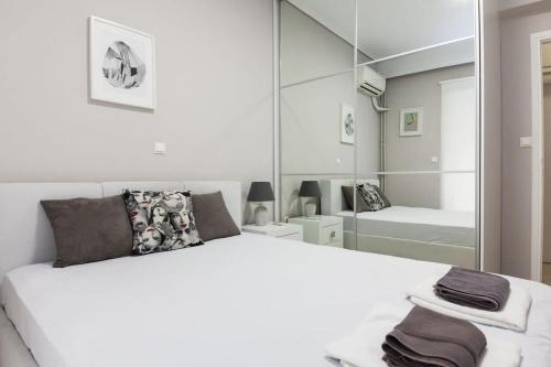 - une chambre avec un grand lit blanc et un miroir dans l'établissement Modern Luxury 2 Bedroom Apt in Agios Dimitrios, à Athènes