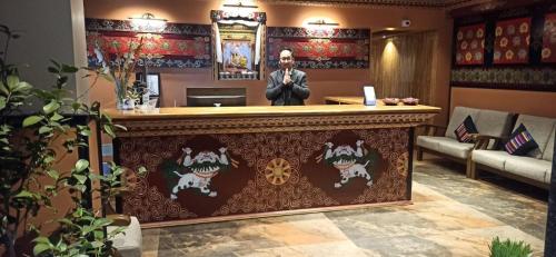 a man standing behind a bar in a waiting room at Gakhil Boutique Hotel in Darjeeling