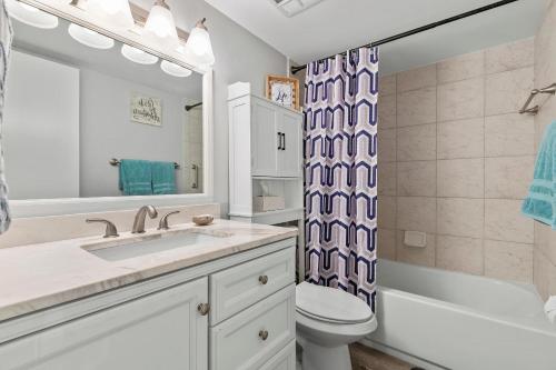 a bathroom with a sink and a toilet and a mirror at Sea Coast Gardens II 115 in New Smyrna Beach