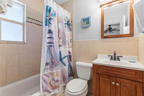 a bathroom with a toilet and a sink and a shower curtain at Flagler Suites 3 in New Smyrna Beach