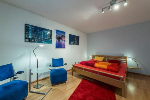 een slaapkamer met een bed, een tafel en blauwe stoelen bij Breubergblick, Stylisches Apartment in Breuberg in Breuberg
