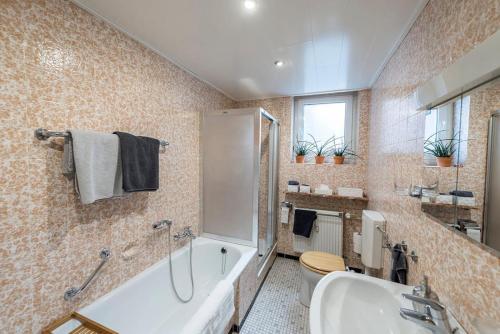 a bathroom with a tub and a toilet and a sink at Breubergblick, Stylisches Apartment in Breuberg in Breuberg