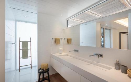 een witte badkamer met een grote spiegel en een wastafel bij Luxury Vacation Villa 21 in Petit Cul de Sac