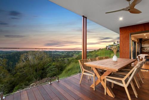 a dining room with a wooden table and chairs on a deck at The Ridge at Maleny Deluxe Residence - Panoramic Valley Views in Maleny