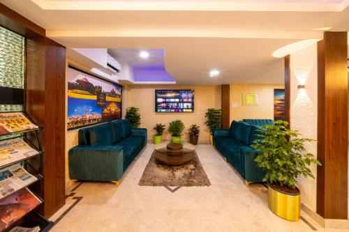 sala de estar con sofás azules y TV en Midtown Suites Marathahalli Bangalore, en Bangalore