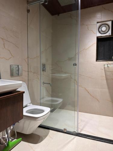 a bathroom with a toilet and a glass shower at House of DB, Luxury Modern Apartment in Jodhpur